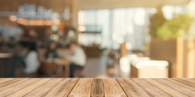Wooden board empty table top on of blurred background. Perspective brown wood table over blur in coffee shop background - can be used mock up for montage products display or design key visual layout.